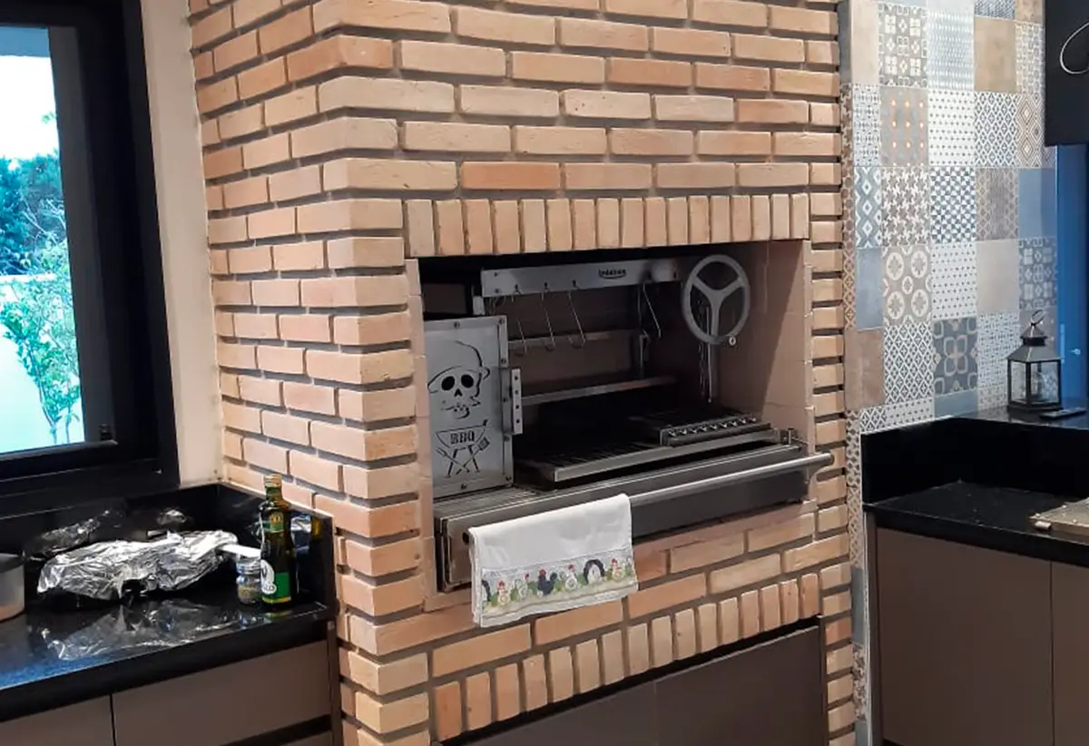 Churrasqueira de tijolinho com grill giratório e azulejo hidráulico ao lado