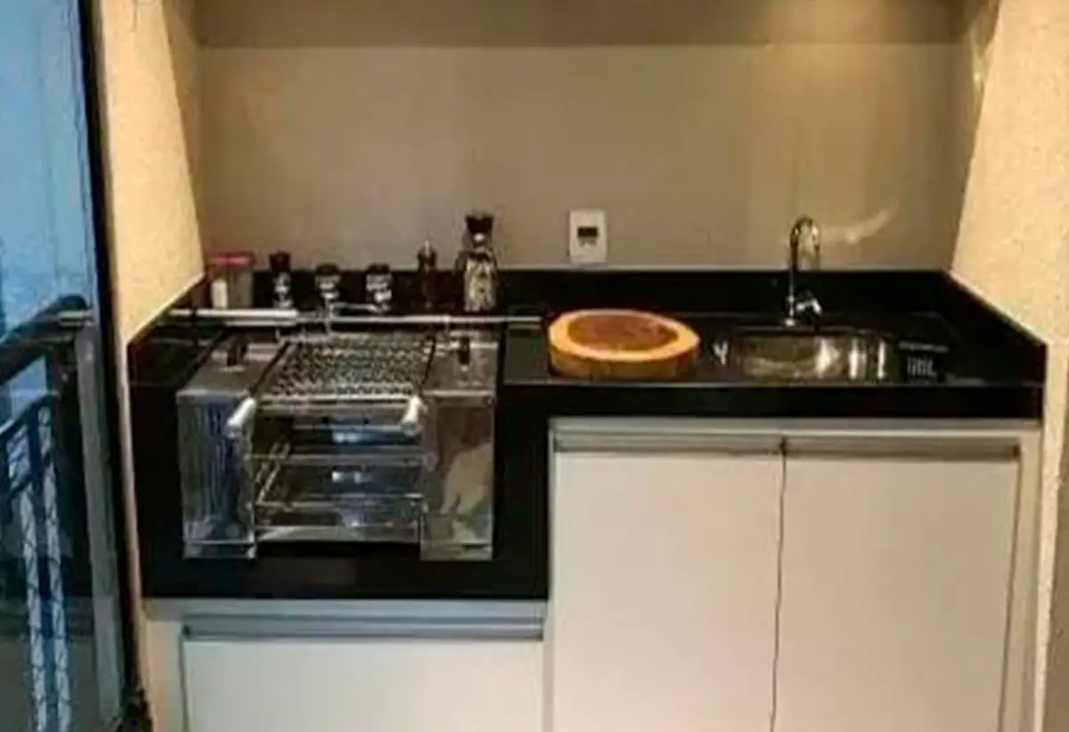 Bancada preta com churrasqueira compacta de inox e tábua redonda de madeira