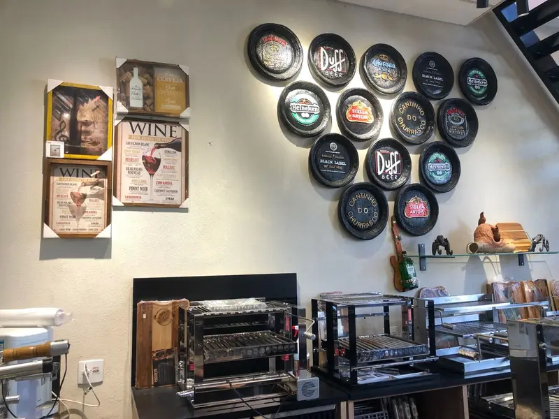 Showroom com parede de placas decorativas e quadros, e churrasqueiras de inox sobre bancada preta