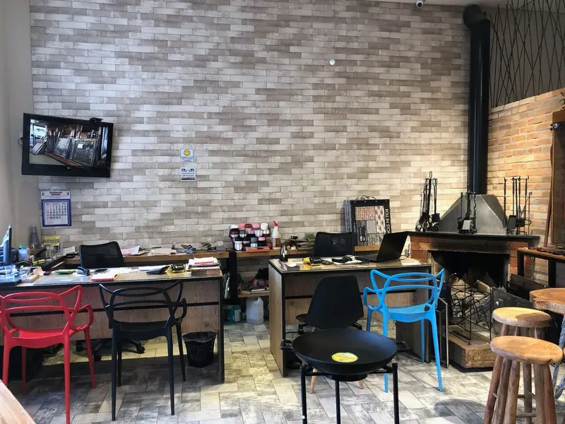 Showroom da Casa João de Barro: mesa de atendimento diante de parede de tijolinho e lareira