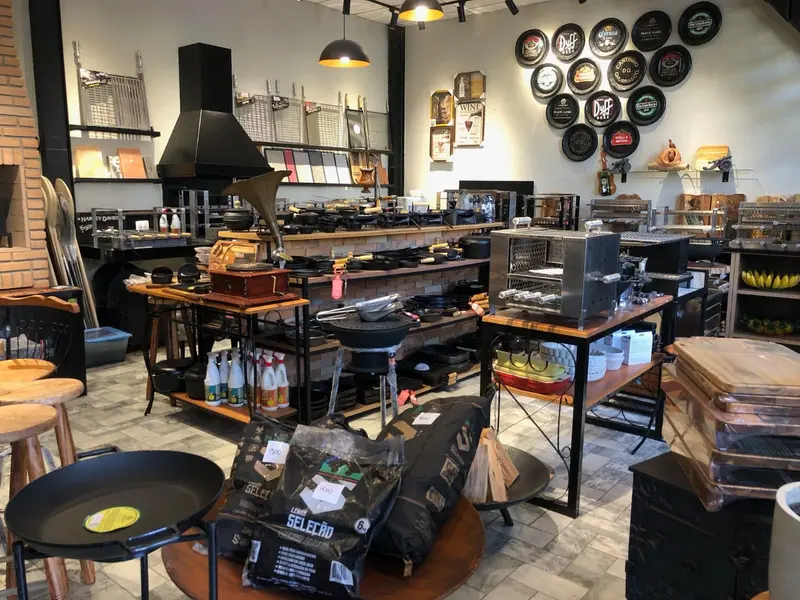 Showroom com churrasqueira de inox, coifa preta e sacos de carvão