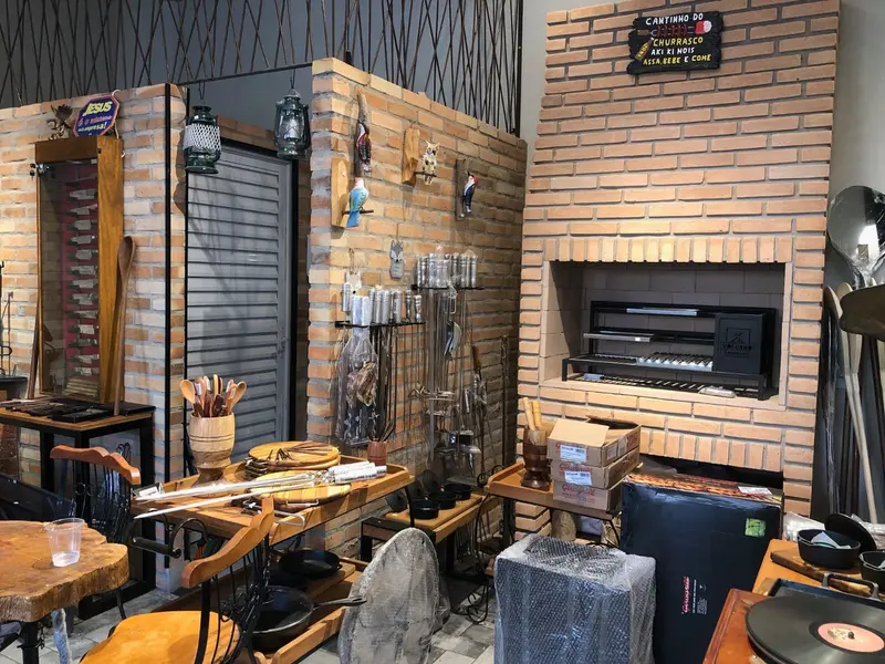 Showroom com churrasqueira de tijolinho, lareira e acessórios pendurados na parede