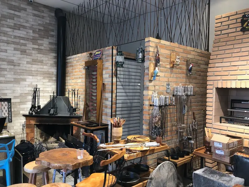 Showroom com lareira, parede de tijolinho e mesa de madeira maciça