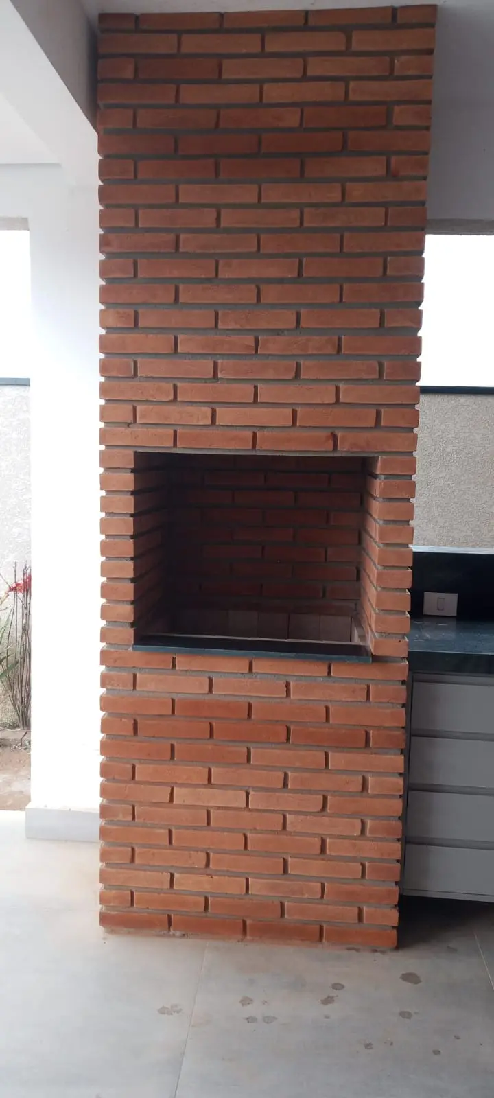 Churrasqueira de tijolo vermelho aparente em área coberta
