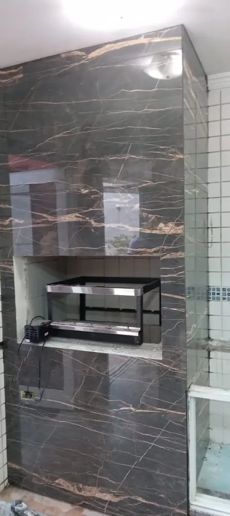 Churrasqueira embutida em porcelanato escuro, com grill de inox