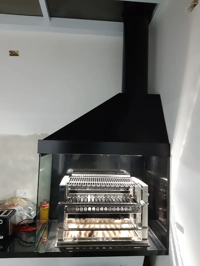 Coifa preta sobre grill de inox com três níveis de grelha