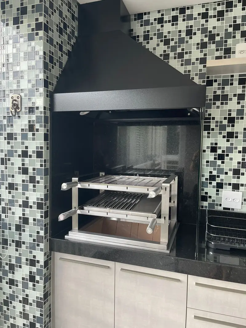 Coifa preta e grill de inox em parede de pastilha preta e branca