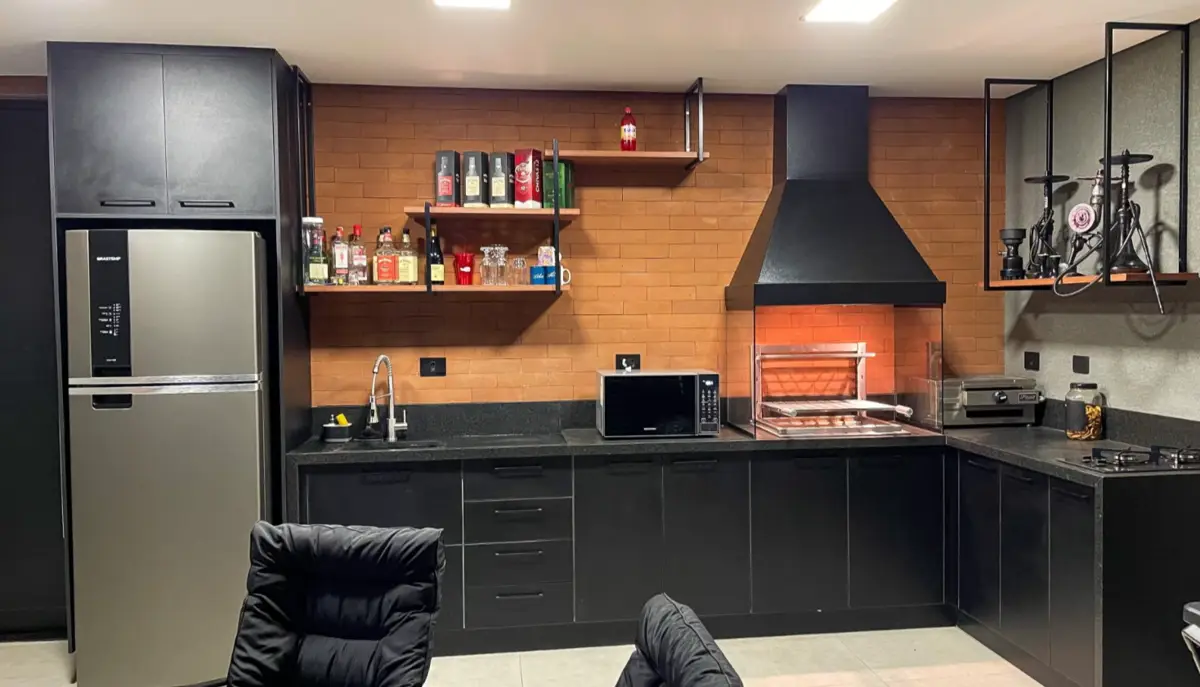 Cozinha gourmet com tijolinho, coifa preta e churrasqueira